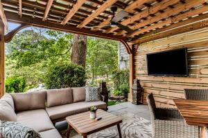 een patio met een bank en een tv aan een houten muur bij Pine Lodge Atlanta - Luxe Atlanta Home Near Everything Hot Tub Patio in Atlanta
