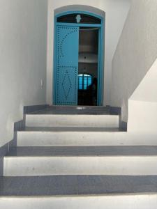 a staircase with a blue door in a building at Maison la perle de Hammam Sousse in Hammam Sousse
