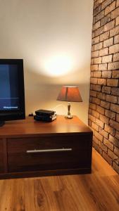 a table with a television and a lamp on it at Leśny Apartament in Białystok