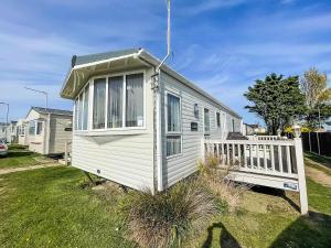 a tiny house with a porch in a yard at Lovely Caravan With Decking Nearby Scratby Beach In Norfolk Ref 50031j in Great Yarmouth