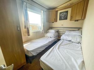 two beds in a small room with a window at Lovely Caravan With Decking Nearby Scratby Beach In Norfolk Ref 50031j in Great Yarmouth
