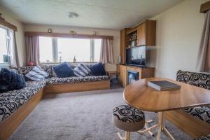 un soggiorno con divano, TV e tavolo di 8 Berth Caravan With Decking At Sunnydale In Lincolnshire Ref 35087s a Louth
