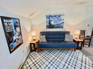 ein Wohnzimmer mit einem blauen Sofa und einem Gemälde an der Wand in der Unterkunft Walk to the Outfield of Lime Rock Park in Salisbury
