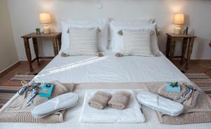 a large white bed with towels and shoes on it at kouremenos beach house East in Angathiás +8 photos