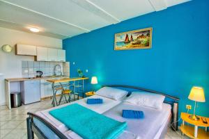 a blue bedroom with a bed and a kitchen at Apartman Studio in Pula