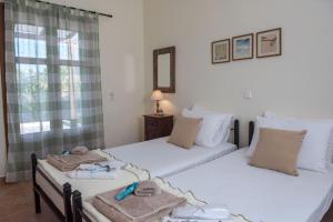 two twin beds in a room with a window at kouremenos beach house East in Angathiás