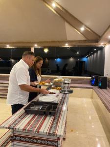a man and a woman standing at a buffet at Natalie Wadi Rum camp & Jeep tour in Wadi Rum