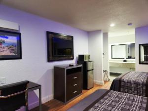 a hotel room with a bed and a flat screen tv at Express Inn Tomball in Tomball