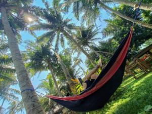 a woman laying in a hammock in a hammock between palm trees at Voulez-Vous in Dickwella