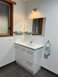 Baño blanco con lavabo y espejo en Greenways Holiday Units, en Tocumwal