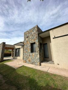 a house with a stone wall next to a yard at Rincón de Chacras de Coria in Ciudad Lujan de Cuyo
