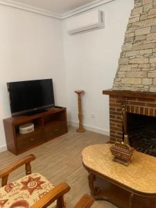 sala de estar con TV y chimenea en El Encanto de Abadía, en Abadía