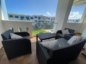 een balkon met stoelen en tafels en een gebouw bij Bel Appartement Vue sur Piscine et Mer in Mansouria