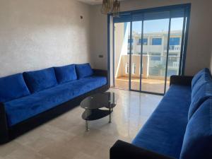 een woonkamer met een blauwe bank en een tafel bij Bel Appartement Vue sur Piscine et Mer in Mansouria