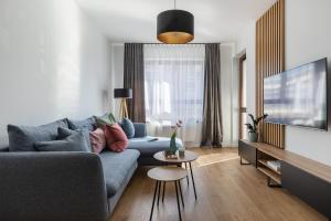 ein Wohnzimmer mit einer blauen Couch und einem Fernseher in der Unterkunft TS New Town Apartments in Stettin