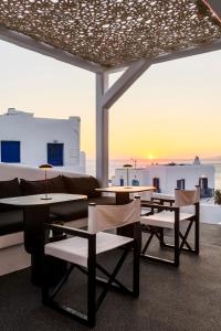 a patio with tables and chairs and a view of the ocean at She Mykonos Boutique Hotel in Mýkonos City