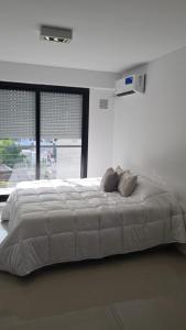 um quarto branco com uma cama grande e uma janela em Francia Uno em Rosário