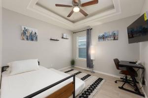 a bedroom with a bed with a ceiling fan and a desk at The Oaks Modern 3Bd/2Ba.Fast WiFi/Netflix in Edinburg