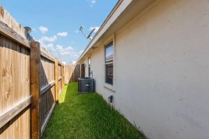 a fence next to a white building with a yard at The Oaks Modern 3Bd/2Ba.Fast WiFi/Netflix in Edinburg