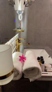 a bathroom with towels on a sink with a pink flower at السبعينات - السودة Seventies -Al-Sodah in Suda