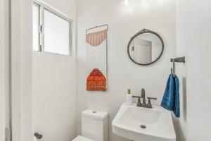 Baño blanco con lavabo y espejo en The Maude House, en Twentynine Palms