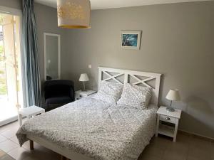 um quarto com uma cama branca e uma cadeira em Studio cosy résidence Odalys 3 Étoiles em La Londe-les-Maures