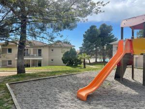 um parque infantil com um escorrega laranja num parque em Studio cosy résidence Odalys 3 Étoiles em La Londe-les-Maures