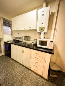 cocina con armarios blancos y microondas en Ubicación Aristides Parque 2 en Mendoza