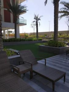 two benches and palm trees in front of a building at Brand New Apartment with Gym and Pool in Dubai