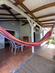 a hammock on a patio with a table and chairs at L'ESCALE TROPICALE in Bouillante