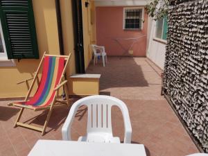 einen weißen Stuhl und zwei Stühle auf einer Terrasse in der Unterkunft Casa Il Carruggio in San Bartolomeo al Mare