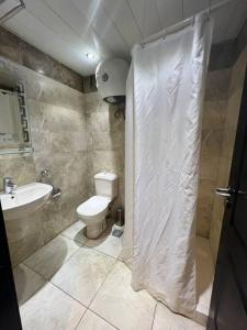 La salle de bains est pourvue de toilettes et d'un rideau de douche. dans l'établissement شاليه ببورتو مارينا على البحر٢ غرفه, à El Alamein