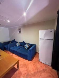 - un salon avec un canapé bleu et un réfrigérateur dans l'établissement شاليه ببورتو مارينا على البحر٢ غرفه, à El Alamein