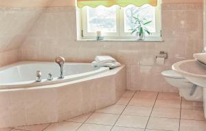 a bathroom with a tub and a toilet and a window at Cozy Apartment In Börgerende-Rethwisch in Börgerende-Rethwisch