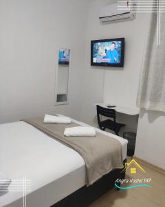 ein Schlafzimmer mit einem Bett und einem TV an der Wand in der Unterkunft Angra Hostel 147 in Angra dos Reis
