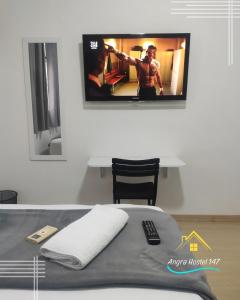 uma televisão pendurada numa parede acima de uma cama em Angra Hostel 147 em Angra dos Reis