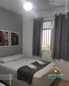 um quarto com uma cama grande e uma janela em Angra Hostel 147 em Angra dos Reis