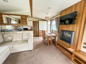 a living room with a couch and a television and a table at Lovely Caravan With Decking At Millfields Caravan Park Ref 87025f in Skegness