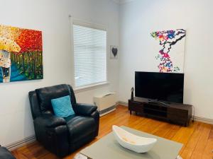 a living room with a chair and a television at Central Hut Villa in Lower Hutt