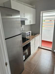uma cozinha com um frigorífico de aço inoxidável e uma janela em El Gengo Hostel em Madri
