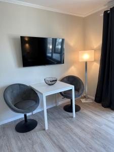 Zimmer mit 2 Stühlen, einem Tisch und einem TV in der Unterkunft Traumhafte Ferienwohnung "Seeperle" in Cuxhaven - Duhnen mit Teilseeblick in 1A Lage in Cuxhaven