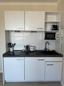 una cucina bianca con lavandino e forno a microonde di Traumhafte Ferienwohnung "Seeperle" in Cuxhaven - Duhnen mit Teilseeblick in 1A Lage a Cuxhaven