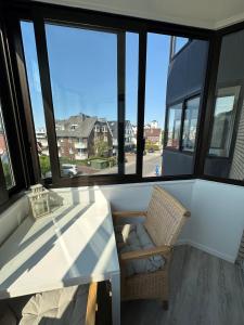 una mesa y una silla en una habitación con ventanas en Traumhafte Ferienwohnung "Seeperle" in Cuxhaven - Duhnen mit Teilseeblick in 1A Lage, en Cuxhaven