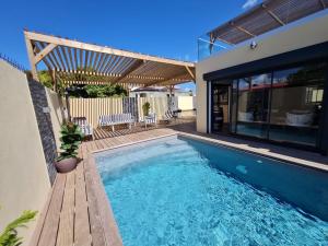 una piscina con terraza de madera y una casa en Villa Jasmin Standing Piscine Chauffee 4 Ch 9 Pers, en Baie-Mahault