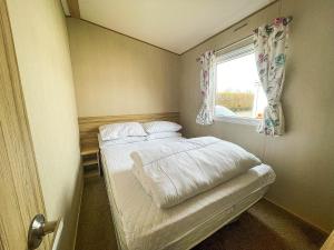 a small bedroom with a bed and a window at Caravan With Decking At Southview Holiday Park In Skegness Ref 33005s in Skegness