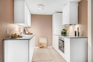 a kitchen with white cabinets and a sink at Sentral v Nidelva in Trondheim