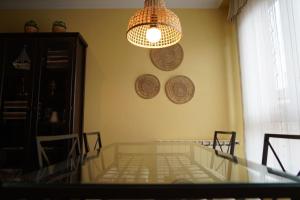 a dining room with a glass table and a chandelier at ALMAR, Apartamento en Luanco. in Luanco