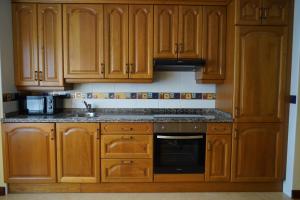 une cuisine avec des armoires en bois et un four à plaques de cuisson dans l'établissement ALMAR, Apartamento en Luanco., à Luanco