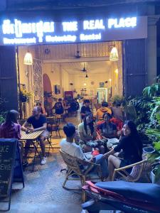 The Real Place Hostel في باتامبانغ: مجموعة من الناس يجلسون على الطاولات في المطعم