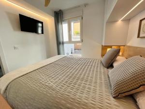 a bedroom with a large bed with a television on the wall at El Piset 124 in Benissa